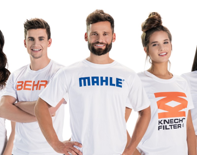 Person wearing a MAHLE t shirt surrounding by others in t-shirts of our family of brands such as BEHR and KENCHT FILTER. 
